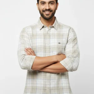 Man wearing a beige checked casual shirt with rolled sleeves and dark blue denim jeans